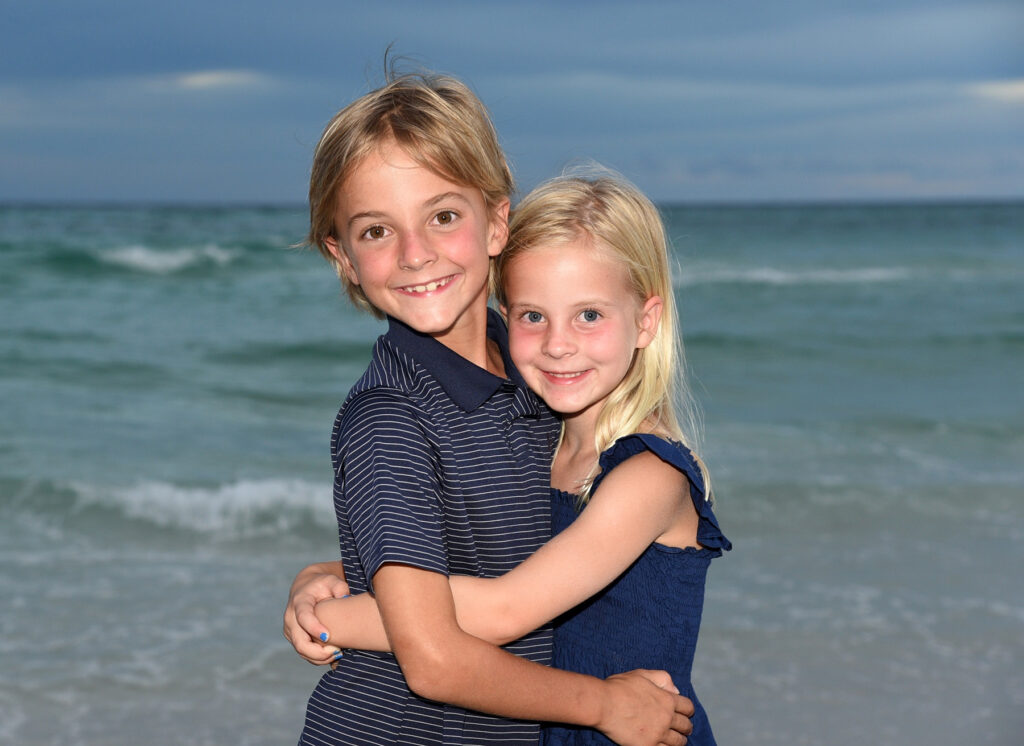 Sibling beach photo, hugging in front of Gulf.